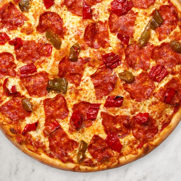 Close-up of a Pizza Nova pizza with pepperoni, melted cheese, and red and green peppers.