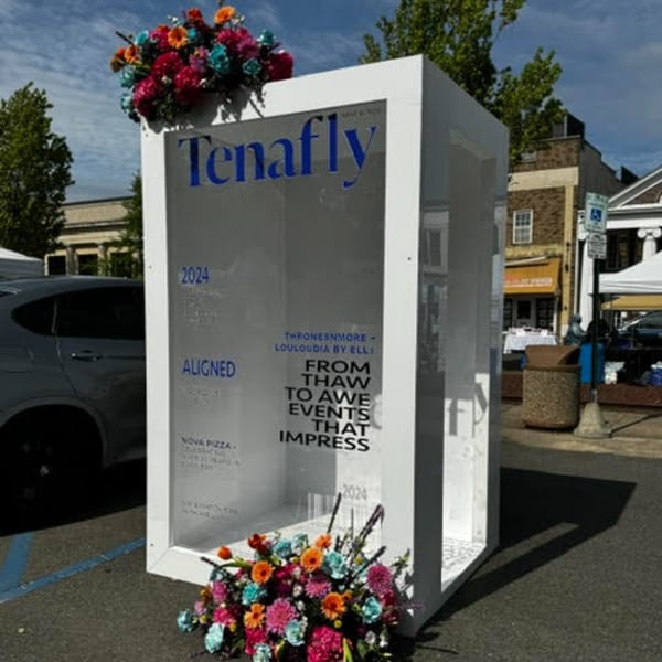 A white display box with "Tenafly" and "Nova Pizza" text, adorned with colorful flowers.