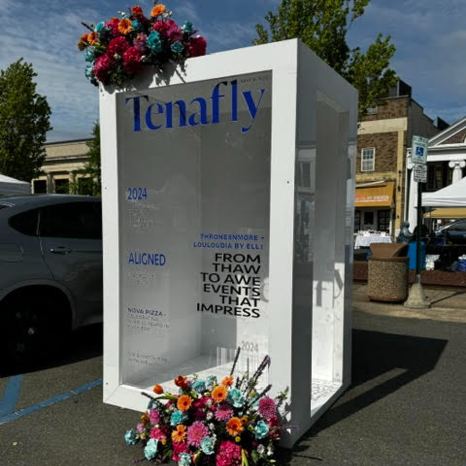 A white display box with "Tenafly" and "Nova Pizza" text, adorned with colorful flowers.