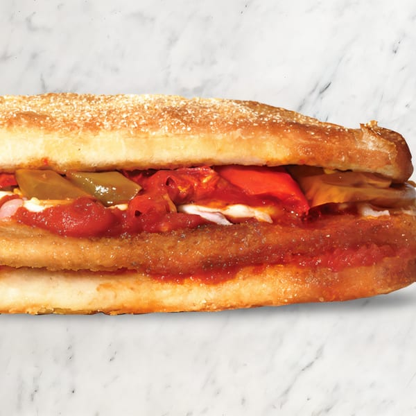 A close-up of a Pizza Nova sandwich filled with red sauce, cheese, and green peppers.