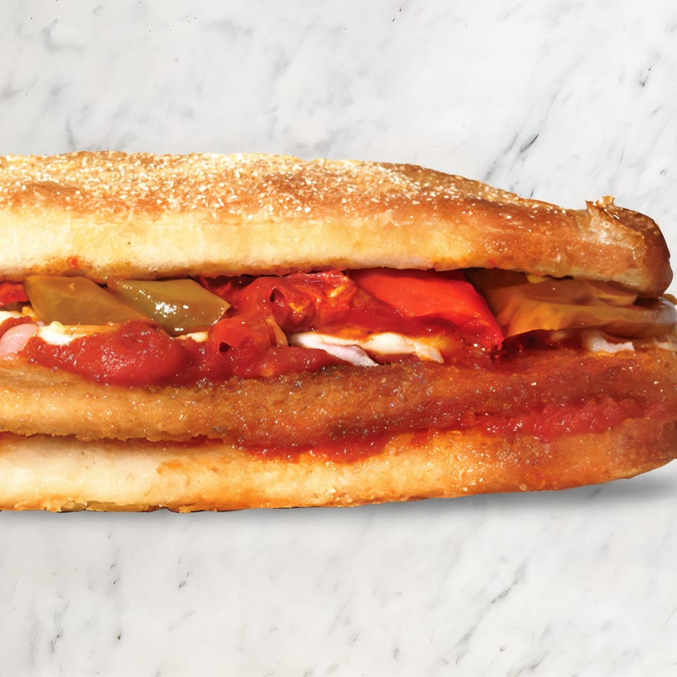 A close-up of a Pizza Nova sandwich filled with red sauce, cheese, and green peppers.